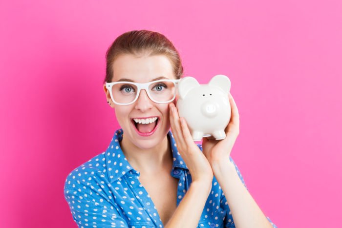 Young woman with a piggy bank on pink background